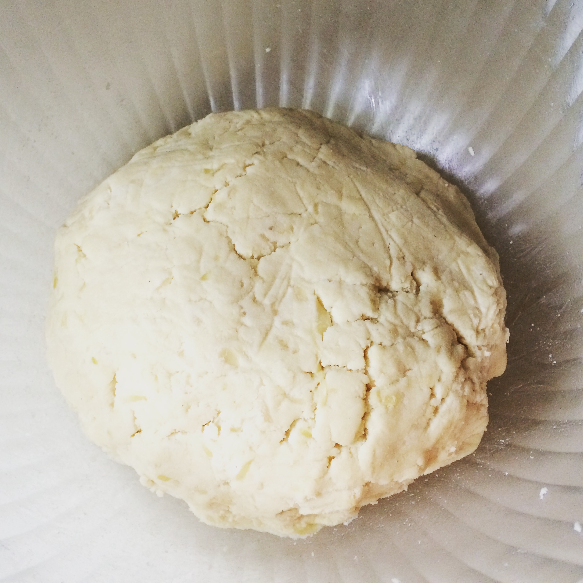 Clear bowl with dough ball in center, kneaded.
