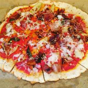 Pizza with toppings on a piece of parchment paper, edges of crust are browned.