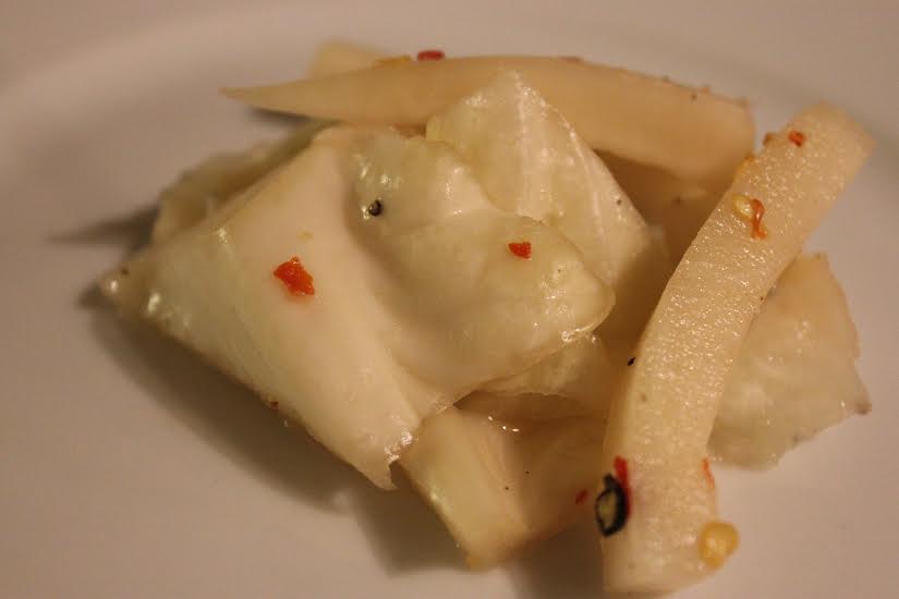 Close up of cabbage and daikon vegetable after pickling, on a white plate.