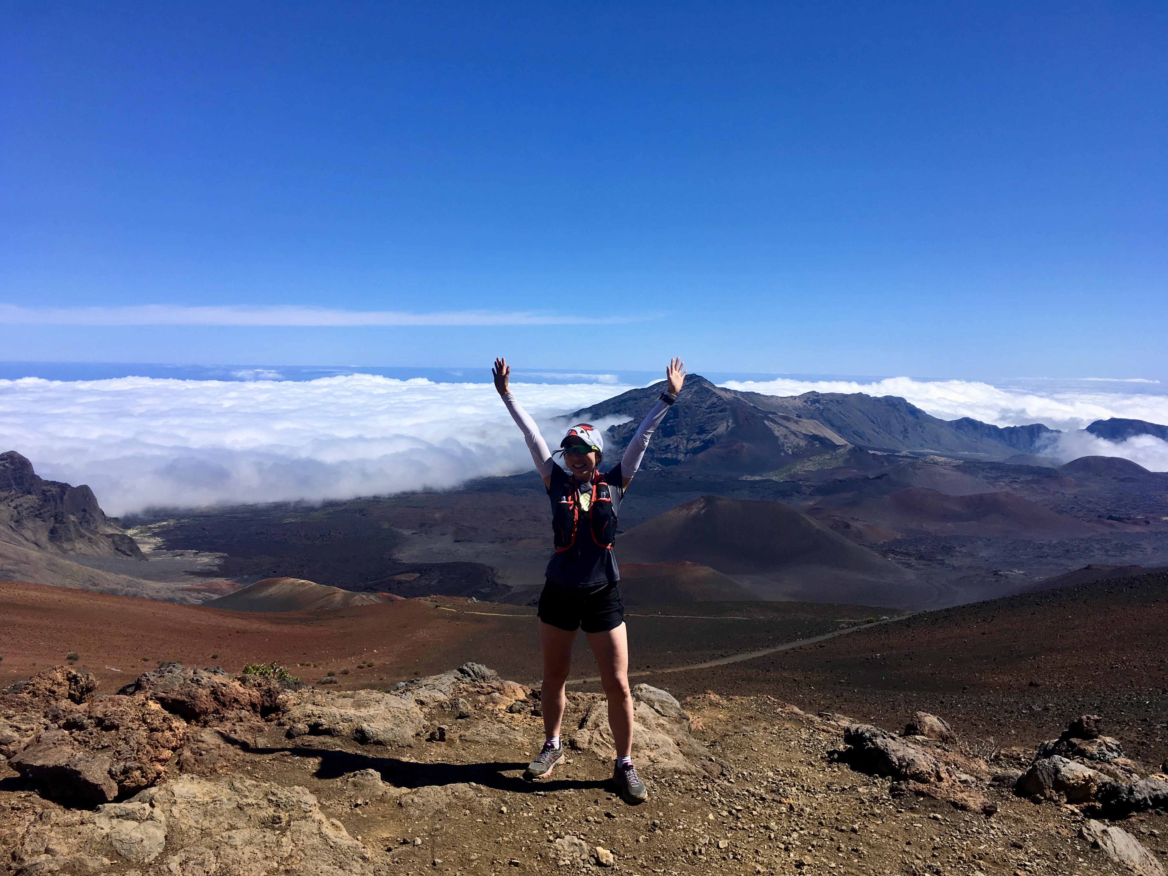 Author standing on the edge of the Haleakala Crater trail under blue skies.
